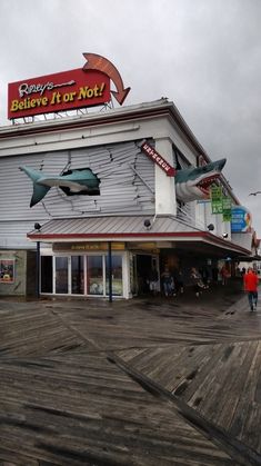 people are walking around in front of a building with shark sculptures on the side of it