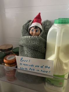 an elf in a towel with a sign on the shelf next to milk and yogurt