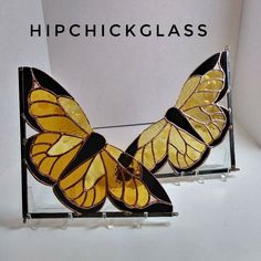 a yellow and black butterfly on display in front of a sign that reads, hip chickglass