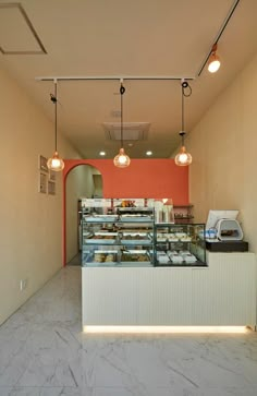 the inside of a restaurant with orange walls and white counter tops, along with lights hanging from the ceiling