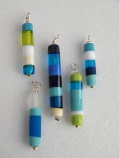 four pieces of glass sitting on top of a white table next to some silver beads