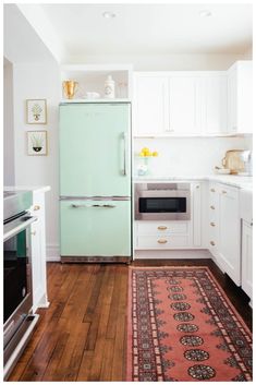 a kitchen with an oven, refrigerator and rug on the wooden floor in front of it