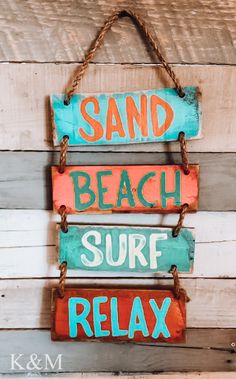 a sign that says sand, beach, surf and relax hanging on a wooden wall