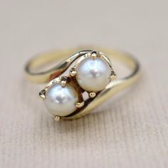 Vintage 14k gold ring set with two cultured pearls in a toi et moi style. In French "Toi et Moi" means "you and me." This style of ring has romantic connotations, and can be used as an alternative engagement ring. Era: c.1970s Markings: None Materials: 14k Gold, Cultured Pearls (4.63mm each) Weight: 2.5 grams Ring Size: 5.5 (comes with one free resizing by our jeweler) Condition: Excellent vintage condition with minor surface wear from age  Shipping is free in the United States  Follow us on Instagram @LUXXORVintage Vintage Akoya Pearl Jewelry For Anniversary, Classic White Bypass Ring For Formal Occasions, Classic Gold Bypass Ring For Wedding, Anniversary Akoya Pearl Yellow Gold Ring, Classic Oval Bypass Ring For Wedding, Timeless 14k Gold Pearl Ring For Anniversary, Elegant Hallmarked Bypass Ring For Anniversary, Timeless Yellow Gold Pearl Ring For Anniversary, Elegant White Rings For Anniversary Gift