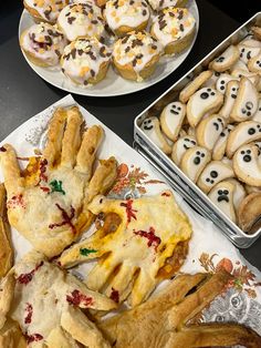 two trays filled with cookies and pastries on top of a black table next to each other