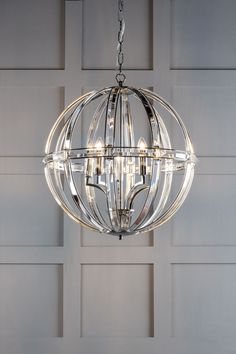 a chandelier hanging from the ceiling in front of a wall with white paneling