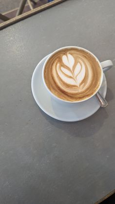 a cappuccino on a saucer with a leaf design in the foam