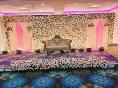 a stage set up for a wedding with flowers on the floor and an ornate bench