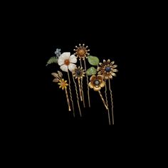 three flower hair pins with leaves and flowers on them in gold, white, and blue