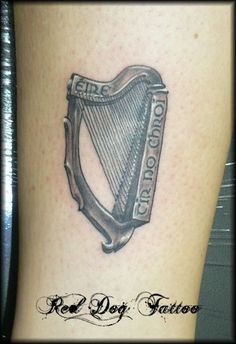 a black and white photo of a tattoo with a harp on the side of a woman's leg