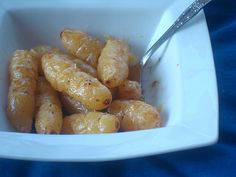 a white bowl filled with food on top of a blue cloth covered table next to a spoon