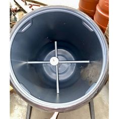 a large metal bowl sitting on top of a cement floor next to potted plants