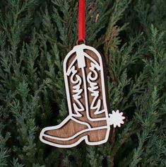 a wooden ornament hanging from a tree with the word cowboy on it's boot