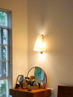 a bedroom with a mirror, dresser and lamp on the wall next to a window