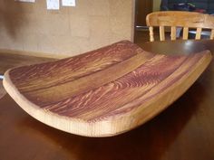 a wooden bowl sitting on top of a table next to two chairs and a wall