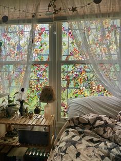 a bedroom with two large stained glass windows above the bed and side table in front of it