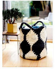 a black and white bag sitting on top of a wooden floor next to a potted plant