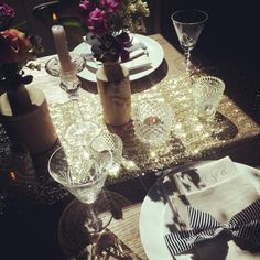 the table is set with plates and wine glasses, silverware, candles, and flowers