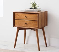 a small wooden table with two drawers and a plant on top