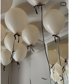 white balloons are tied to the ceiling with black ribbon