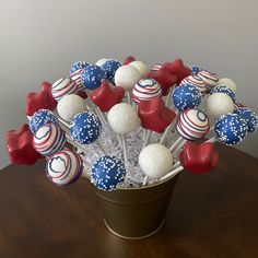 a vase filled with red, white and blue cake pops on top of a wooden table