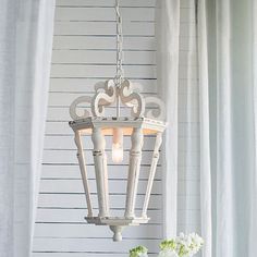 a white chandelier hanging from the ceiling in a room with curtains and flowers