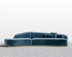 a blue couch sitting on top of a floor next to a white wall with two pillows