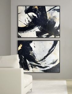 two black and white paintings hanging on the wall next to a couch in a living room