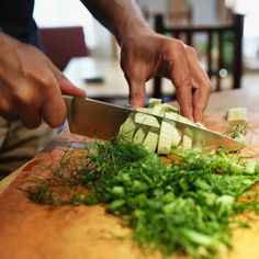 a person cutting up vegetables on top of a wooden table