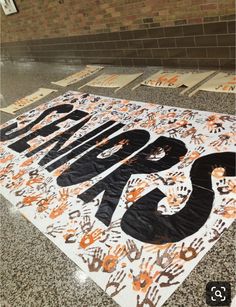 an orange and black sign on the ground in front of a brick wall with writing