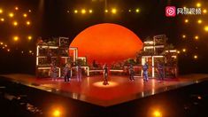 the stage is lit up with bright lights and people standing on it in front of an orange ball