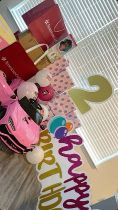 a pink scooter sitting on top of a wooden floor next to a birthday sign