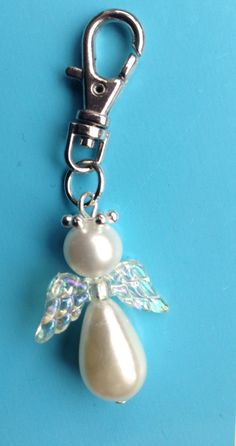 a keychain with an angel charm attached to it on a blue background,