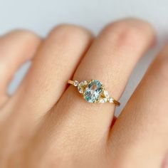 a woman's hand holding a ring with an aqua and white diamond in it