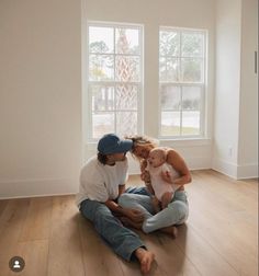 a man and woman sitting on the floor with a baby