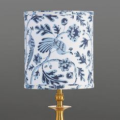 a blue and white lamp on a table with a gold frame around the lampshade