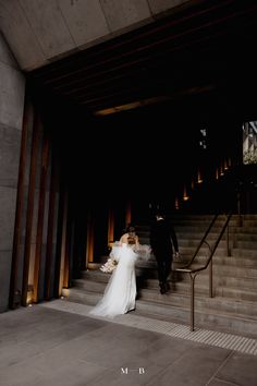 the bride and groom are walking down the stairs