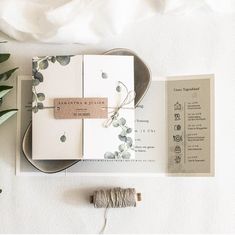 the wedding stationery is laid out on top of each other, along with some flowers and twine