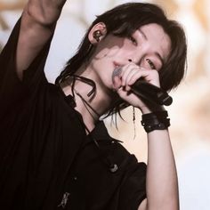 a woman with black hair and piercings holding a microphone up in the air while standing on stage