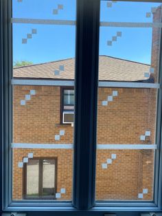 two windows with tape taped to them in front of a brick building and blue sky