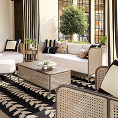 a living room with wicker furniture and black and white striped curtains on the windowsill