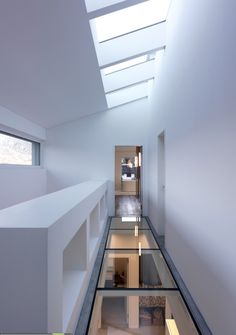 a long narrow hallway with skylights on the ceiling and windows in the wall, leading to another room