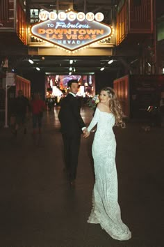 a bride and groom holding hands in front of the welcome to fabulous las vegas sign