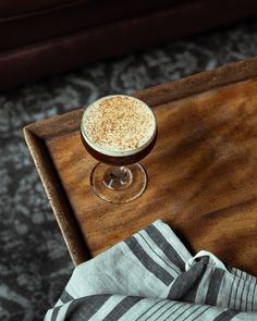 a drink sitting on top of a wooden table next to a striped napkin and cloth