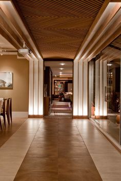 an empty hallway with tables and chairs in the center is lit by recessed lights