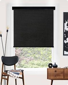 a black roller shade in a living room with a chair and painting on the wall