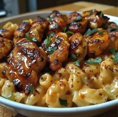 a bowl filled with macaroni and cheese covered in chicken meatballs, garnished with parsley