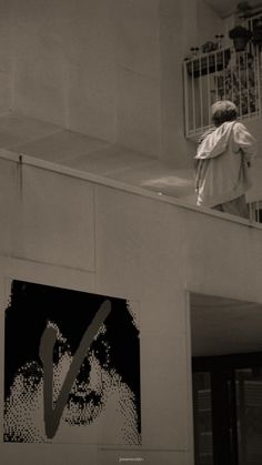 a man standing on top of a balcony next to a poster with the letter v