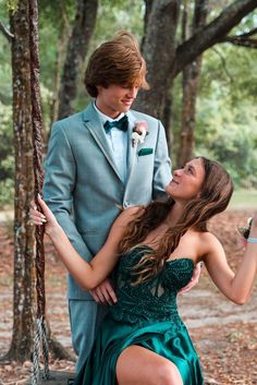 a man in a gray suit and woman in a green dress on a rope swing