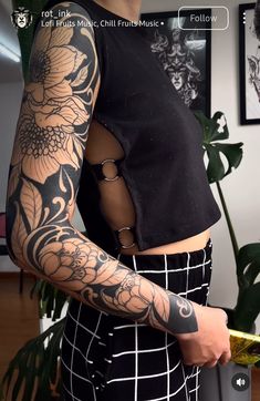 a woman with tattoos on her arm and shoulder is holding a piece of paper in her hand